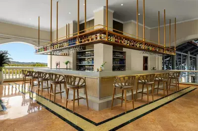 a bar in a building with a bunch of bar stools at Wyndham Alltra Punta Cana All Inclusive Resort in Punta Cana