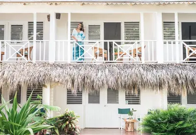 a woman standing on the balcony of a house at El Mosquito Boutique Hotel Playa Bonita in Las Terrenas