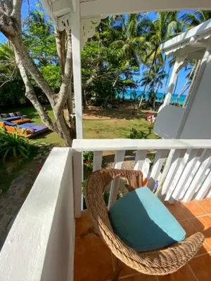 a wicker chair sitting on the porch of a house at El Mosquito Boutique Hotel Playa Bonita in Las Terrenas
