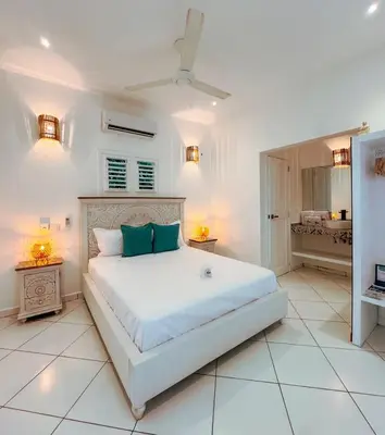 a white bedroom with a large bed with blue pillows at El Mosquito Boutique Hotel Playa Bonita in Las Terrenas