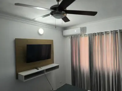 a living room with a television and a ceiling fan at Las Palmeras RIKI R in Boca Chica