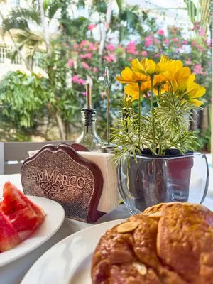 a table with plates of food and a vase with flowers at Hotel San Marco in Santo Domingo