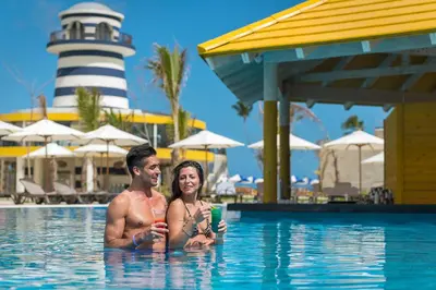 a man and woman in the swimming pool with a lighthouse at El Beso Adults Only At Ocean El Faro - All Inclusive in Punta Cana