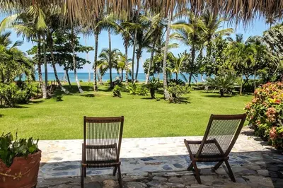 two chairs in a park with palm trees and the ocean at Villa Flamboyan in Las Galeras