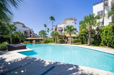 a swimming pool with palm trees and buildings at Xeliter Balcones del Atlantico - Las Terrenas in Las Terrenas