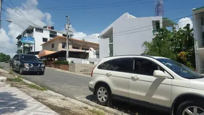 a white car parked on the side of a street at TERRAZAS DEL CARIBE, APARTA HOTEL. in Santo Domingo