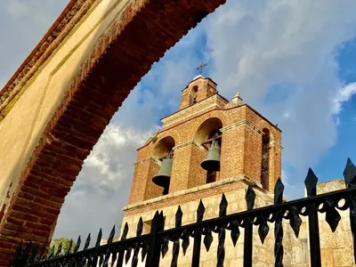 a tall clock tower behind a brick fence at Paseo Colonial - Ermitage #5 in Santo Domingo