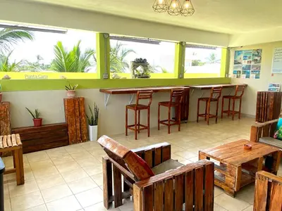 a restaurant with a bar with wooden chairs and tables at Hostel Eco Punta Cana in Punta Cana