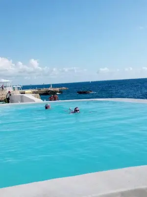 two people swimming in a swimming pool near the ocean at Apartamentos y habitaciones sol dominicus SOLO ADULTOS in La Laguna