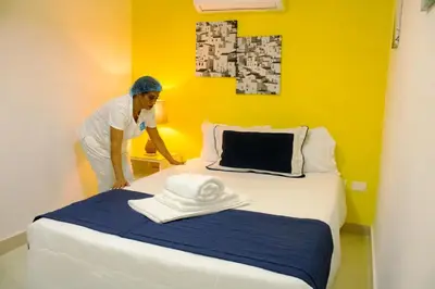 a woman standing next to a bed in a room at Malecon Rooms y Hotel in Santo Domingo