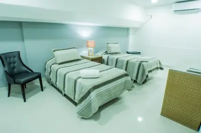 a room with two beds and a chair in it at Malecon Rooms y Hotel in Santo Domingo