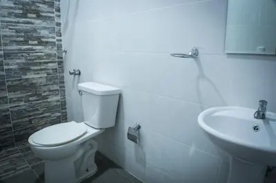a white bathroom with a toilet and a sink at Malecon Rooms y Hotel in Santo Domingo
