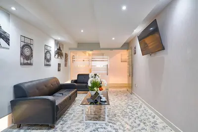 a living room with a leather couch and a tv at Malecon Rooms y Hotel in Santo Domingo