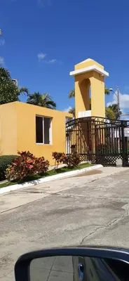 a yellow house with a gate in front of a street at Residencial Palmas De Gurabo in Santiago de los Caballeros
