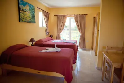 a room with two beds with red sheets at Kite Beach Inn in Cabarete