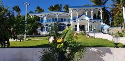 a blue and white house with palm trees in front of it at casaenjoysamana in Los Naranjos