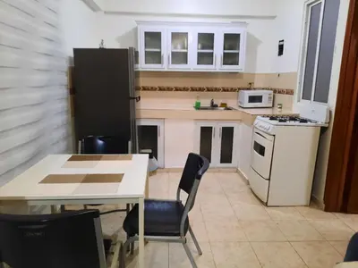 a small kitchen with a table and a refrigerator at J. B Apartamentos in Santo Domingo