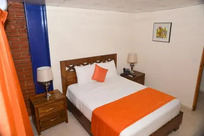 a bedroom with a bed with an orange and white blanket at Hotel Jaraba in Jarabacoa