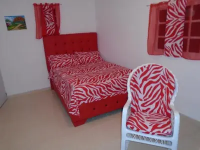 a red bed and a chair in a room at Guesthouse Villa La Isla in La Romana