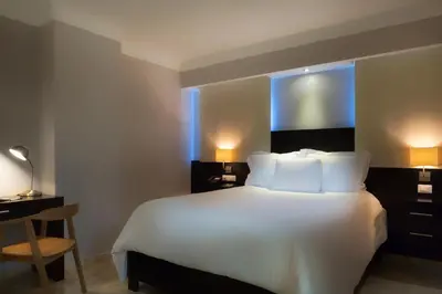 a bedroom with a large white bed and a desk at Plaza Florida Suites in Santo Domingo