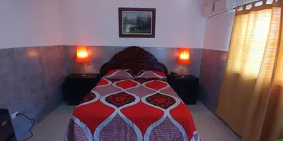 a bedroom with a bed with a red and white comforter at Hotel Riparbella in Santo Domingo