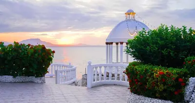 a white gazebo and some flowers and the water at Piergiorgio Palace Hotel in Sosúa