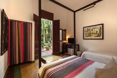 a bedroom with two beds and a desk and a window at Hotel Villa Colonial in Santo Domingo