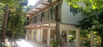 a house with a balcony in the middle of trees at Los Palmares Guest House & Eventos in San Cristóbal