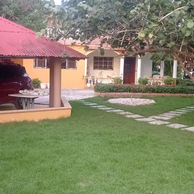 a house with a lawn and a table in front of it at Los Palmares Guest House & Eventos in San Cristóbal