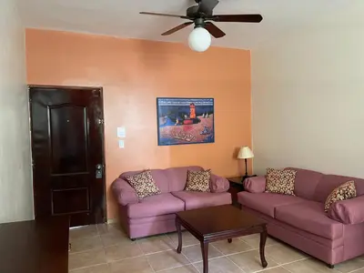 a living room with purple couches and a ceiling fan at Apartahotel Alvear in Santo Domingo