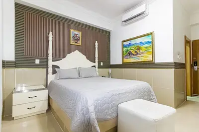 a bedroom with a white bed with a white comforter at Hotel La Casona Dorada in Santo Domingo