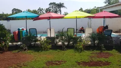 a group of umbrellas and chairs next to a pool at Villa de Colores 3 Rooms 5 king Beds in Sosúa