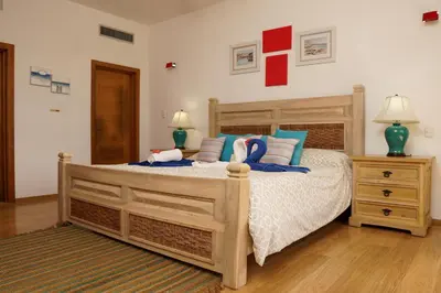 a bedroom with a large wooden bed with blue pillows at Sybaris Suites & Residences in Juan Dolio