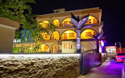 a building with a palm tree in front of it at Hotel Las Palmeras in Sosúa