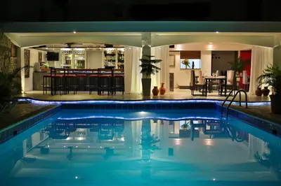 a swimming pool at night with a bar in the background at Hotel Las Palmeras in Sosúa