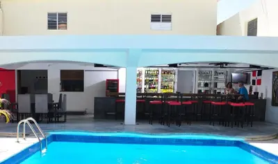a pool with a bar and a restaurant with a table at Hotel Las Palmeras in Sosúa