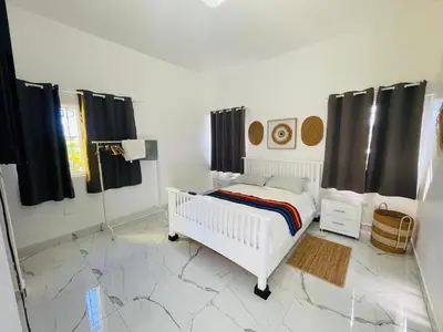 a bedroom with a white bed and black curtains at Playa Dorada Mountainview Villa in San Felipe de Puerto Plata