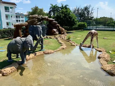 a group of statues of elephants and a giraffe drinking water at Casa Coral Sosua in Sosúa
