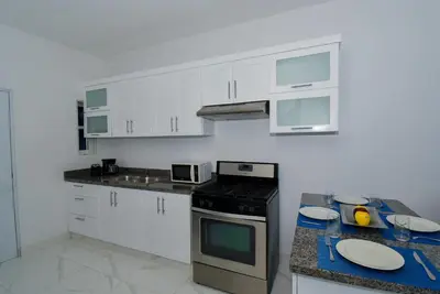 a kitchen with white cabinets and a black stove top oven at Rosil Place in San Felipe de Puerto Plata