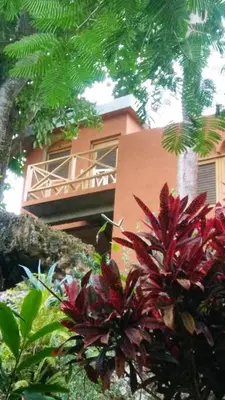 a pink building with red plants in front of it at Welcoming House in Las Galeras with Stunning Sea View in Las Galeras