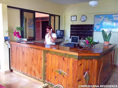 a woman talking on a cell phone at a reception desk at Residence Meridiana in Juan Dolio