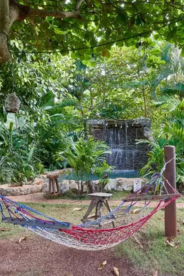 a hammock in front of a fountain in a garden at CHALET TROPICAL Hotel & Pool Bar Restaurant in Las Galeras