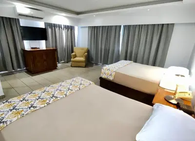 a hotel room with two beds and a chair at Micro Hotel Condo Suites in Santo Domingo