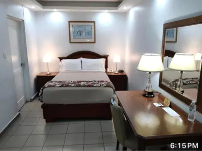 a bedroom with a bed and a desk and a mirror at Micro Hotel Condo Suites in Santo Domingo