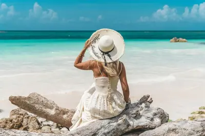 a woman in a hat sitting on the beach at Hotel Villa Serena in Las Galeras