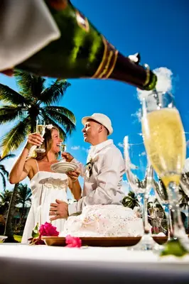 a bride and groom sitting at a table drinking champagne at Hotel Villa Serena in Las Galeras