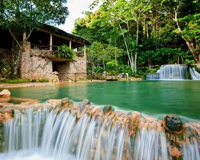 a waterfall in a pool of water with a building at Paraiso Caño Hondo in Los Guineos Perdidos