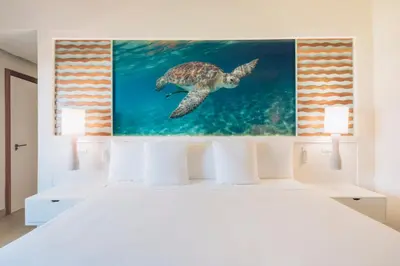 a white bedroom with a turtle painting on the wall at Iberostar Selection Coral Bavaro - All Inclusive in Punta Cana