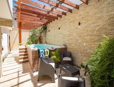 a patio with a pool and chairs and a brick wall at Home W Private Hot Tub, Near Everything in Sosua Center in Sosúa