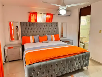 a bedroom with a large bed with orange pillows at 1Dom Rep - Huge cozy 3 bedrooms - close to all transportation Jacobo Majluta - Residencial Paradise V Colina Arroyo 1 in Santo Domingo